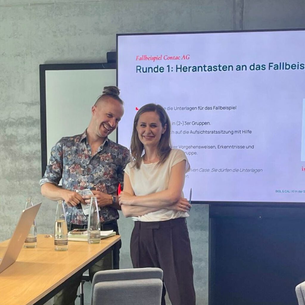 Sebastian Winkler mit einer Teilnehmerin vor der Präsentationsfolie „Fallbeispiel Contac AG" während eines Workshops zu KI im Aufsichtsrat