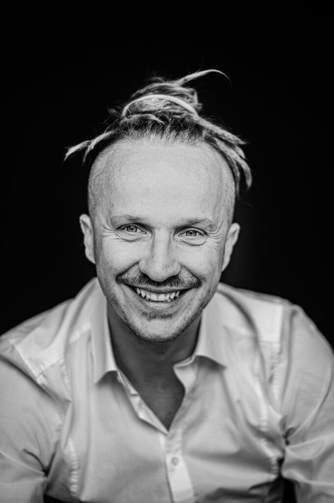 Schwarz-Weiß-Nahaufnahme: Sebastian Winkler lächelt in die Kamera